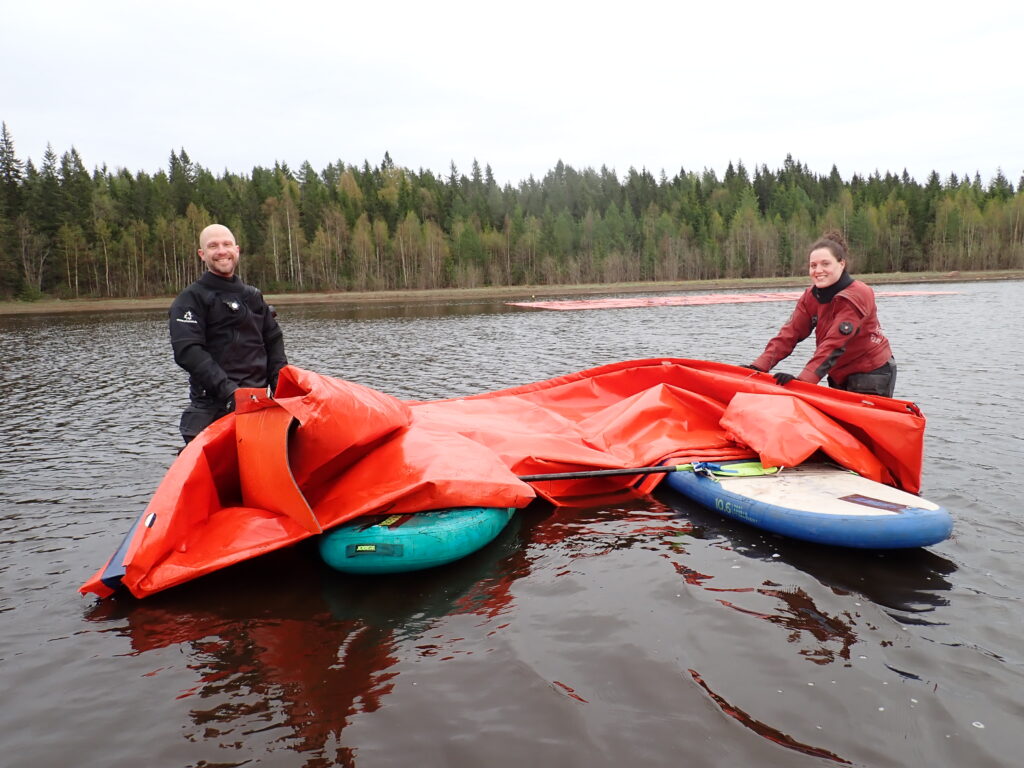 Two persons holding the red cover in the water